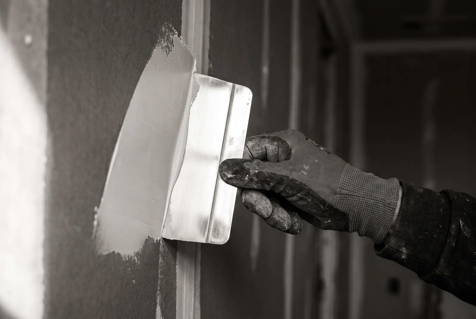 Hand glättet mit dem Spachtel eine Fuge auf einer Gipskartonwand